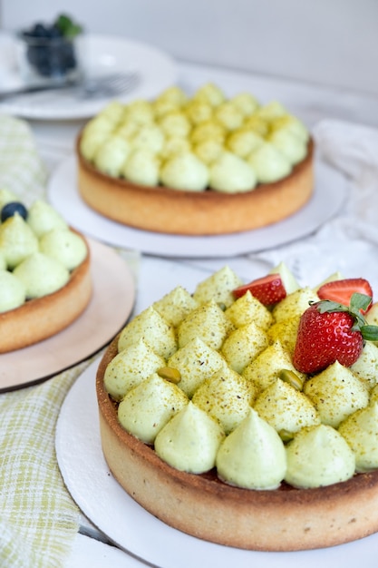 Foto pastel de tres galletas redondas con crema de pistacho verde y mermelada de fresa junto a la ventana