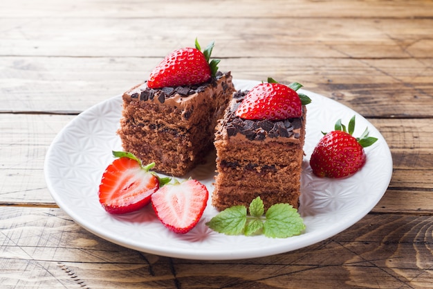 Pastel de trufa de chocolate con fresas y menta. Mesa de madera.