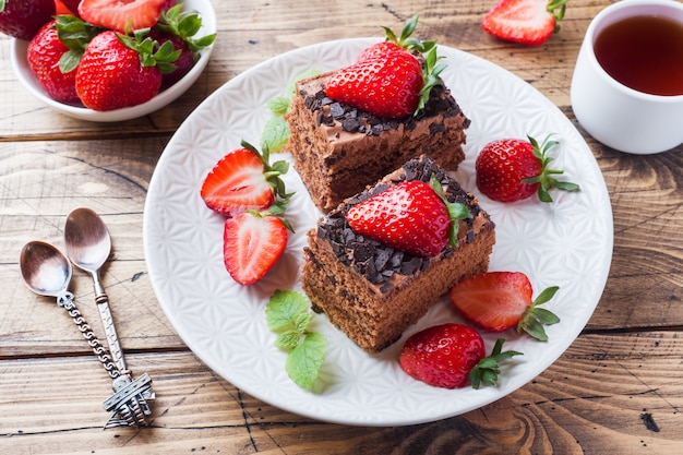 Pastel de trufa de chocolate con fresas y menta. Mesa de madera.