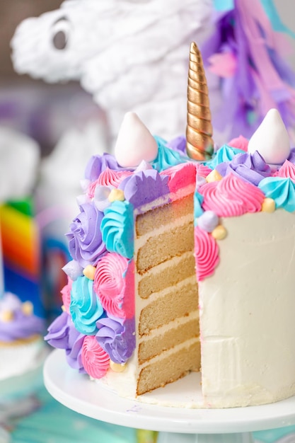 Pastel de unicornio multicapa en rodajas en el puesto de pasteles en la fiesta de cumpleaños de la niña.