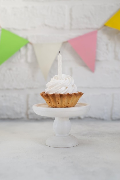 Pastel con una vela en un puesto de pasteles en un fondo de una pared de ladrillo blanco