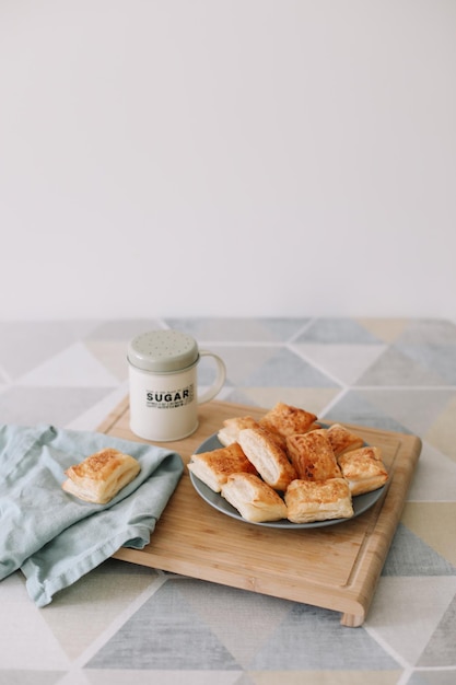 Pastelaria caseira acabada de fazer no pequeno-almoço à mesa da cozinha com pãezinhos folhados e um copo de leite