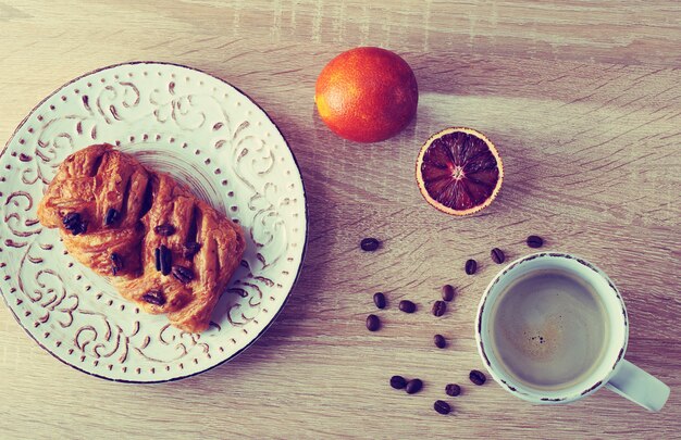 Pastelaria com nozes pecã num prato com uma xícara de café