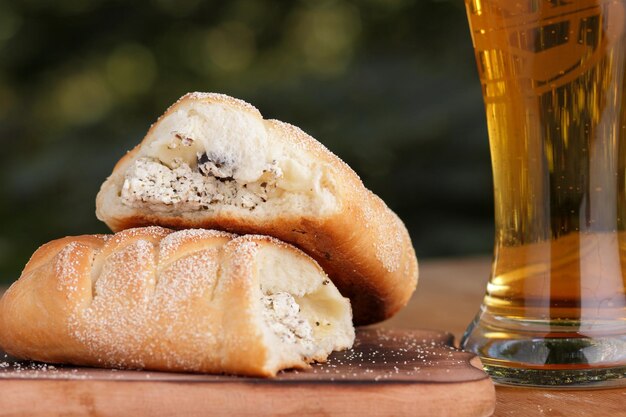 Pastelaria com queijo e azeitonas com um copo de cerveja em um fundo desfocado Copo de cerveja com aperitivos em uma mesa de madeira