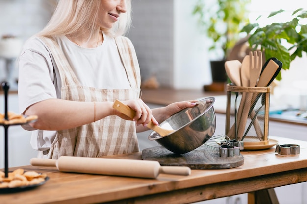 Pastelaria confeiteira jovem mulher caucasiana com tigela de cozinha na mesa da cozinha bolos sobremesa maki