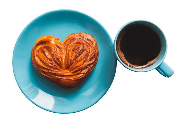 Pastelaria em forma de coração no prato azul e a xícara de café. Isolado em um fundo branco.