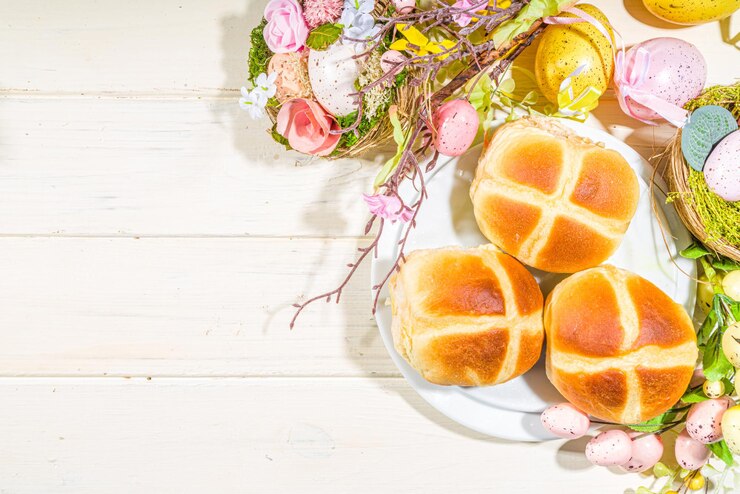Foto pastelaria tradicional, feriado da primavera, páscoa - pãezinhos quentes. no fundo de madeira claro com luz do sol, ovos de páscoa, decoração e ramos de primavera