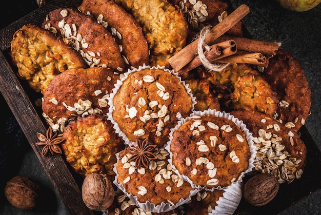 Pastelarias de outono inverno. Comida vegana. Biscoitos caseiros saudáveis, muffins com nozes, maçãs, flocos de aveia. Ambiente acolhedor, cobertor quente, ingredientes. Mesa de pedra escura. vista do topo