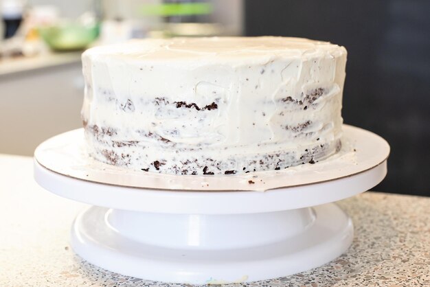 Foto pasteleiro cozinheiro confeiteiro ou padeiro em luvas pretas e avental de cozinha preto faz um bolo. bolo de aniversário feito em casa. conceito de pastelaria caseira, cozinhar bolos, hobby. pequena empresa doméstica feminina.