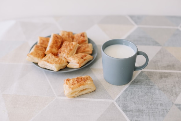 Pastelería casera recién horneada en la mesa de la cocina desayuno con bollos de hojaldre y un vaso de leche