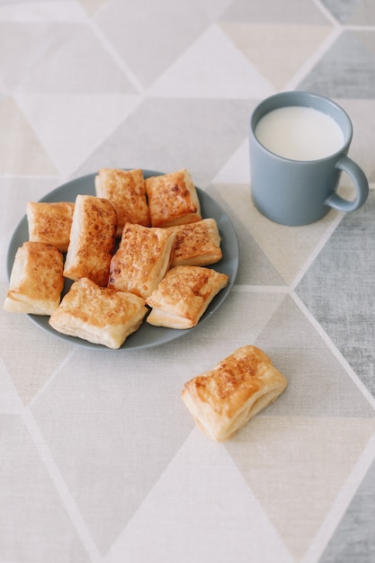 Pastelería casera recién horneada en la mesa de la cocina desayuno con bollos de hojaldre y un vaso de leche