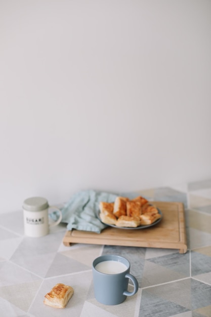 Pastelería casera recién horneada en la mesa de la cocina desayuno con bollos de hojaldre y un vaso de leche