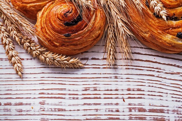 Pastelería dulce con pasas espigas de trigo dorado en concepto de comida y bebida de tablero de madera vintage