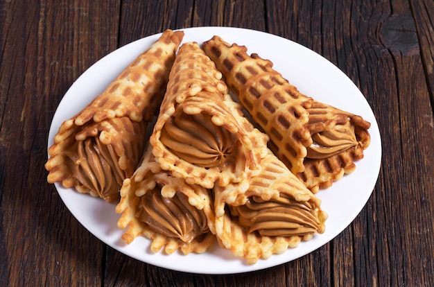 Pastelería con leche condensada hervida en placa sobre mesa de madera oscura.