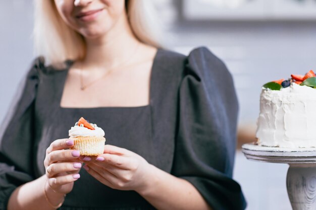 Pastelero confitero joven mujer caucásica con pastel en la mesa de la cocina