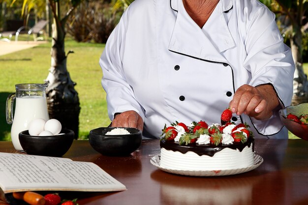 Pastelero haciendo tortas de fresa con chocolate