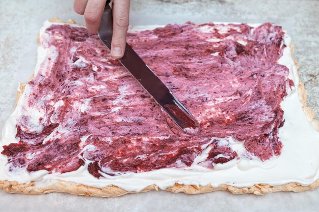 El pastelero jefe lubrica el merengue con crema de bayas confitadas