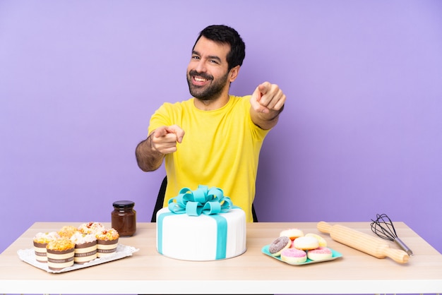 Foto pastelero con mesa llena de dulces