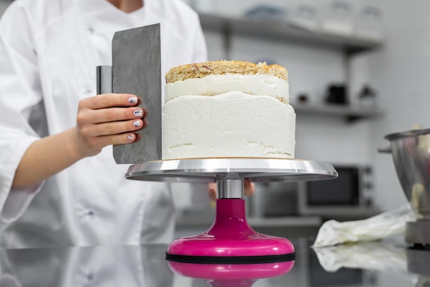El pastelero nivela el pastel con crema