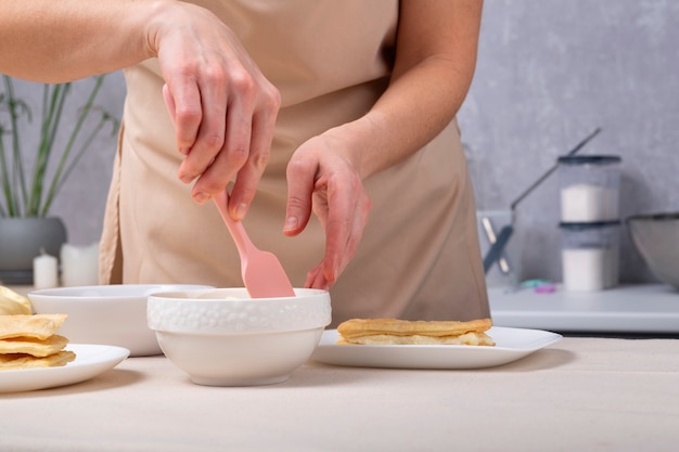 El pastelero prepara la crema para el pastel. Proceso de elaboración de tartas. Manos con vajilla