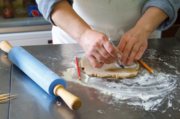 Pastelero trabaja con masa en una mesa en una pastelería, corta formas