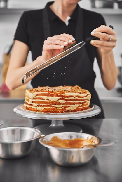 Pastelero con uniforme negro mientras trabaja en confitería el flujo de trabajo en la cocina