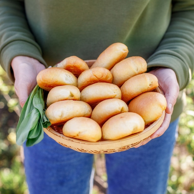 Pasteles amarillos recién horneados en la mano de la mujer, primer plano