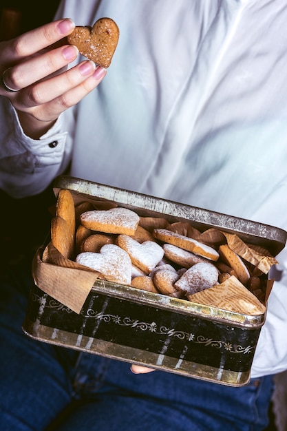 Pasteles caseros para el Día de San Valentín - niña sosteniendo una caja retro con galletas de jengibre en forma de corazón