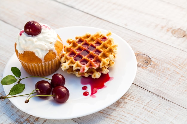 Pasteles con cereza en un plato blanco sobre tablas de madera