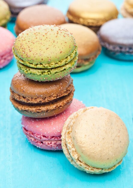 Pasteles de macarons coloridos de lujo francés sobre fondo de madera azul con azúcar en la parte superior