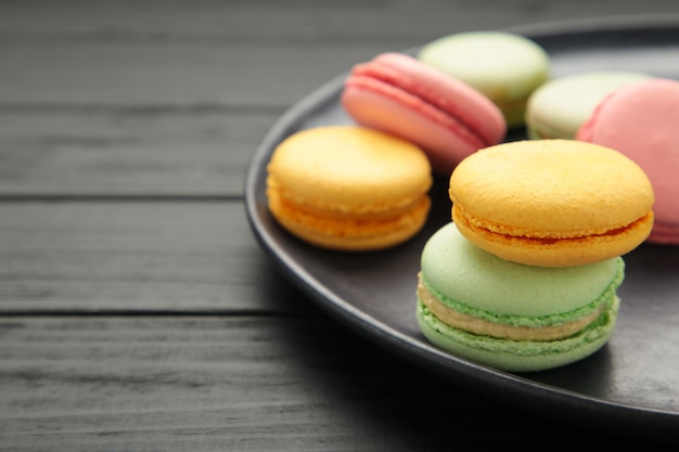 Pasteles de macarons coloridos sobre fondo negro Pequeños pasteles franceses en placa Espacio para texto