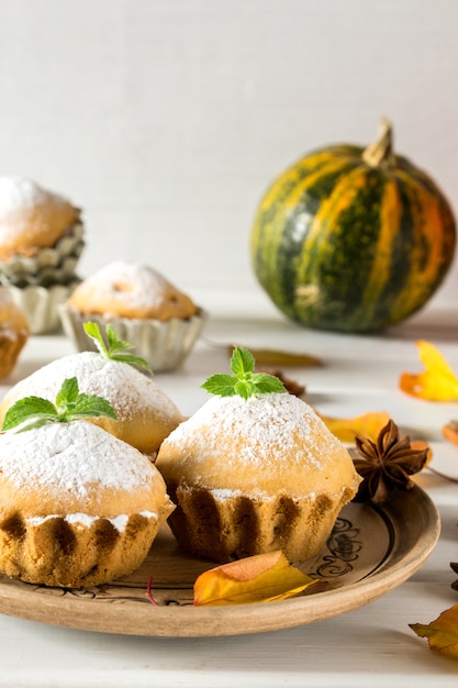 Pasteles de otoño. Magdalenas caseras con azúcar en polvo con canela, estrellas de anís, calabazas, bayas de escaramujo y hojas de otoño