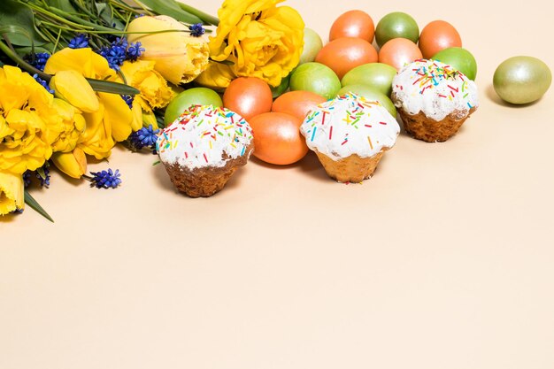 Pasteles de Pascua huevos y tulipanes amarillos sobre un fondo beige