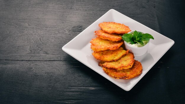 Pasteles de patata con crema agria Tortitas de patata Cocina ucraniana Sobre el fondo de madera vieja Espacio libre para texto Vista superior