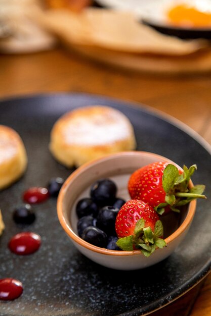 Pasteles de queso con bayas en un plato adornado con mermelada desayuno saludable