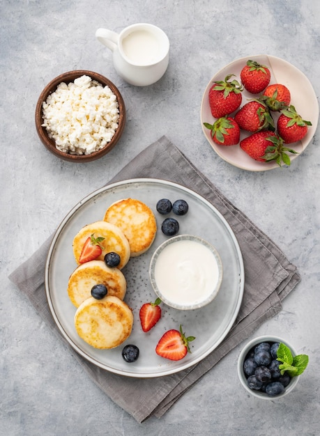 Pasteles de queso o requesón con crema agria fresca y leche sobre un fondo gris El concepto de desayuno saludable y delicioso Vista superior