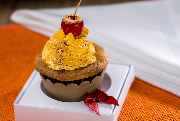 Pastelitos amarillos con cereza, sobre fondo naranja.