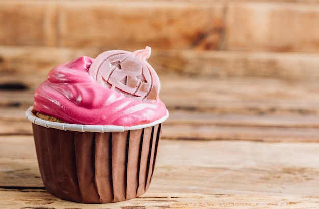 Pastelitos de calabaza de Halloween felices decorados con crema rosa y chocolate colorido sobre fondo de madera rústica Enfoque selectivo con espacio de copia
