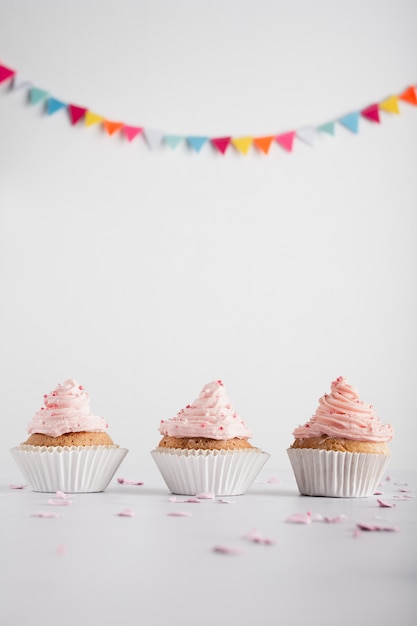 Foto pastelitos de cumpleaños con glaseado y guirnalda