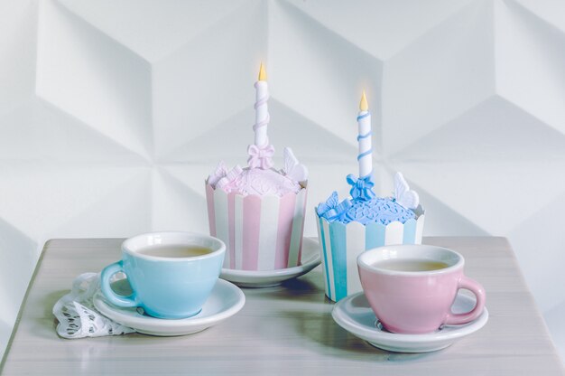 Pastelitos de cumpleaños con velas de cumpleaños y tazas de té