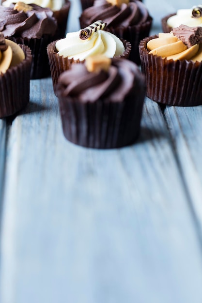 Pastelitos decorados con caramelo de chocolate y glaseado de vainilla sobre un fondo de madera