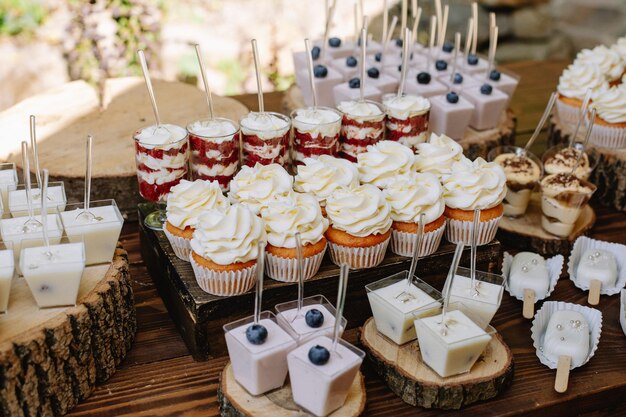 Pastelitos de muffins brillantes y tiramisú en soportes de madera en una boda rústica