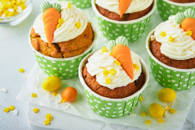 Foto pastelitos de pastel de zanahoria para pascua pastelitos de zanahoria con glaseado de queso crema decorados con pequeñas zanahorias de mazapán sobre fondo blanco feliz pascua y concepto de vacaciones de primavera postre casero de vacaciones