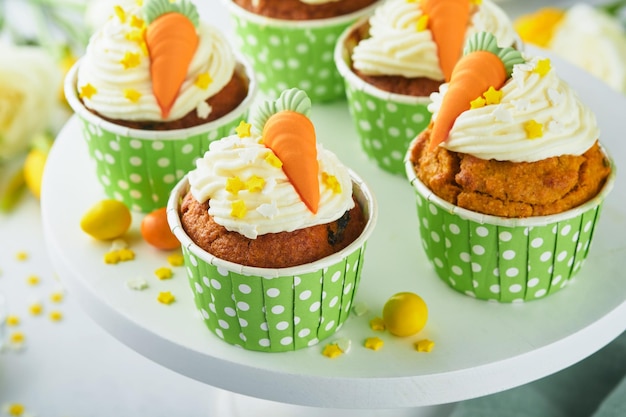 Pastelitos de pastel de zanahoria para Pascua Pastelitos de zanahoria con glaseado de queso crema decorados con pequeñas zanahorias de mazapán sobre fondo blanco Feliz Pascua y concepto de vacaciones de primavera Postre casero de vacaciones