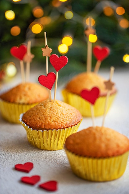 Pastelitos de postre de San Valentín decorados con corazones de madera en mesa blanca Concepto de amor