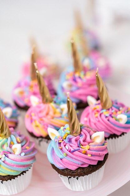 Pastelitos de unicornio decorados con colorido glaseado de crema de mantequilla y chispas.