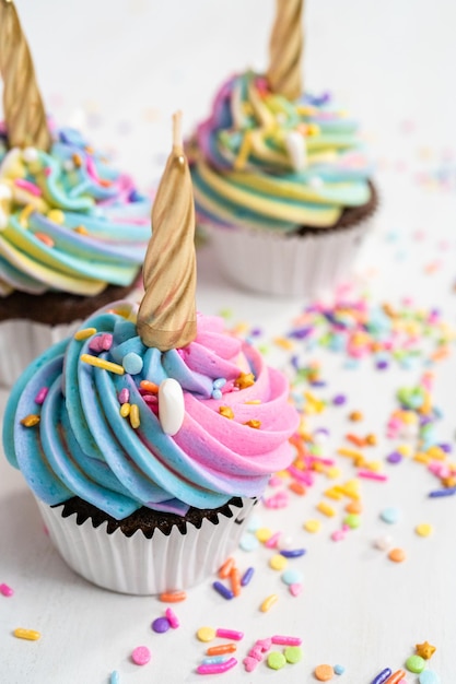 Pastelitos de unicornio decorados con colorido glaseado de crema de mantequilla y chispas.