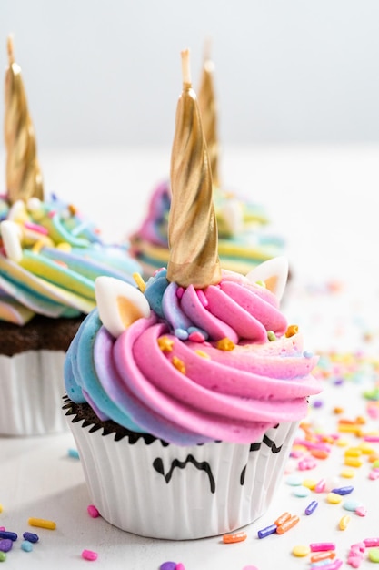 Pastelitos de unicornio decorados con colorido glaseado de crema de mantequilla y chispas.