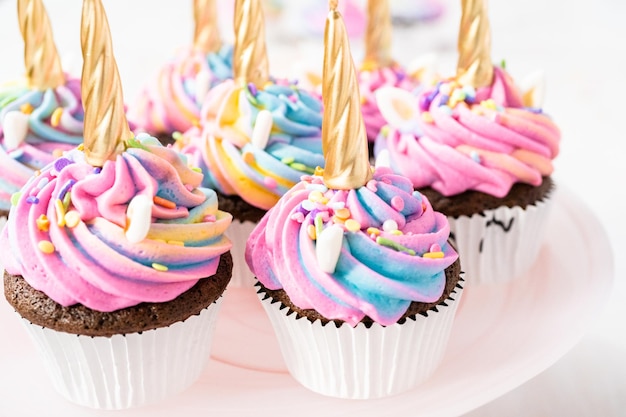 Pastelitos de unicornio decorados con colorido glaseado de crema de mantequilla y chispas.