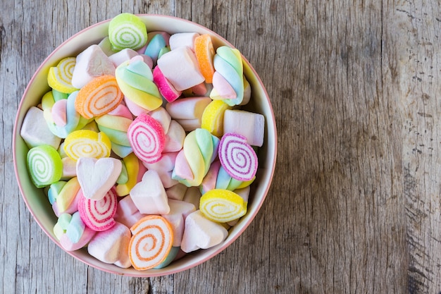 Pastell und colorfu des Eibisches und der gummiartigen Süßigkeit in einer hölzernen Schüssel auf Holztisch.